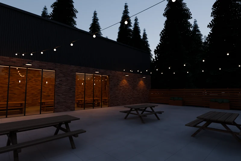 The Brew Lab patio at dusk, with picnic tables under string lights and fir trees along the fence.